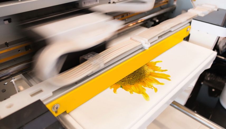 Un T-shirt blanc sur lequel on imprime un motif floral jaune à l'aide d'une machine