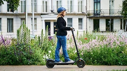 Jeune femme avec un casque sur une trotinnette électrique dans la rue