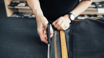 Personne coupant du tissu avec des ciseaux, mesurant avec une règle lors de la production de vêtements.