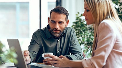 Un homme et une femme regardant un ordinateur portable posé sur une table